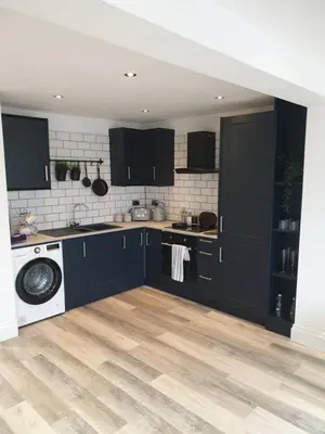 a kitchen with black cabinets and a washing machine at Dora Cottage in Formby