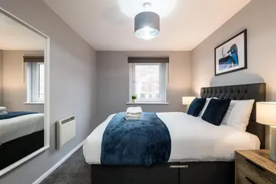 a bedroom with a large bed and a mirror at Fabulous Quayside Apartment with Free Parking in Liverpool