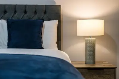 a bed with a blue pillow and a lamp on a table at Fabulous Quayside Apartment with Free Parking in Liverpool