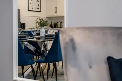 a dining room table with blue chairs and a mirror at Fabulous Quayside Apartment with Free Parking in Liverpool
