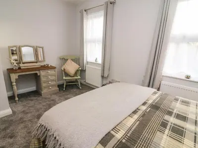 a bedroom with a bed and a mirror and a dresser at Myrtle Cottage in Preston