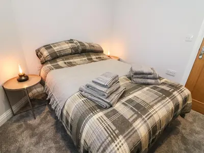 a bedroom with a bed with two pillows and a table at Myrtle Cottage in Preston