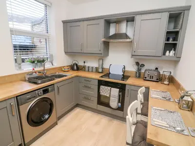 a kitchen with gray cabinets and a washer and dryer at Myrtle Cottage in Preston
