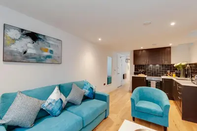 a living room with a blue couch and a kitchen at 80 by Elite in Liverpool
