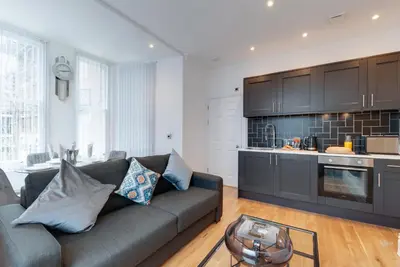 a living room with a couch and a kitchen at 80 by Elite in Liverpool