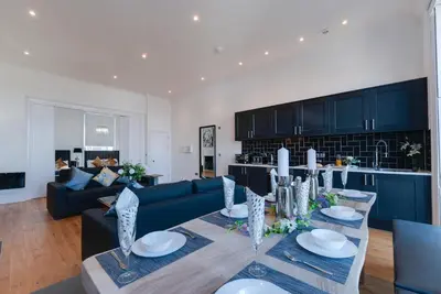 a living room with a table and a blue couch at 80 by Elite in Liverpool
