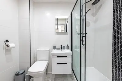 a white bathroom with a toilet and a glass shower at Charles House by Guestz in Preston