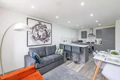 a living room with a couch and a kitchen at Charles House by Guestz in Preston