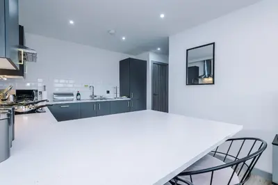 a kitchen with a white counter and blue cabinets at Charles House by Guestz in Preston