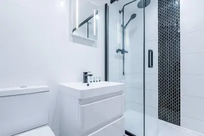 a white bathroom with a sink and a shower at Charles House by Guestz in Preston