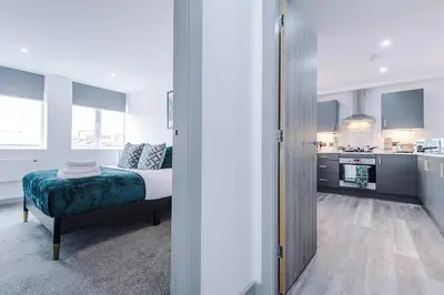 a bedroom with a bed and a kitchen at Charles House by Guestz in Preston