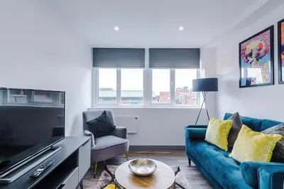 a living room with a blue couch and a tv at Charles House by Guestz in Preston