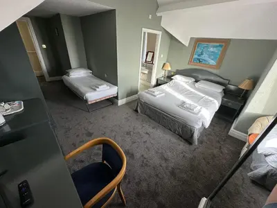 a hotel room with two beds and a desk at Clarkes Hotel Barrow in Furness in Barrow in Furness