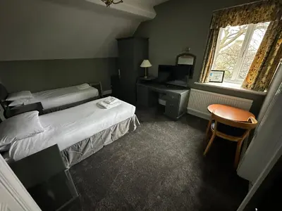 a bedroom with two beds and a desk and a chair at Clarkes Hotel Barrow in Furness in Barrow in Furness