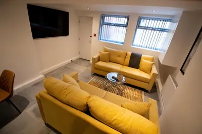 a living room with two yellow couches and a tv at Winter Gardens Suites by Sasco in Blackpool