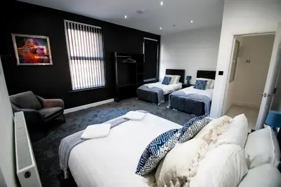 a hotel room with two beds and a chair at Winter Gardens Suites by Sasco in Blackpool