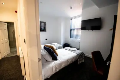 a hotel room with a bed and a television at Winter Gardens Suites by Sasco in Blackpool