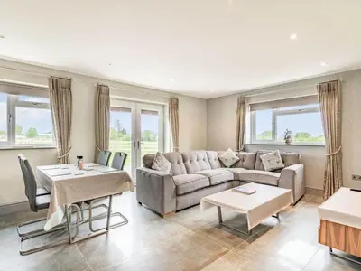 a living room with a couch and tables and windows at Mya Cottage in Wilpshire