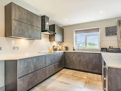 a large kitchen with wooden cabinets and a window at Mya Cottage in Wilpshire