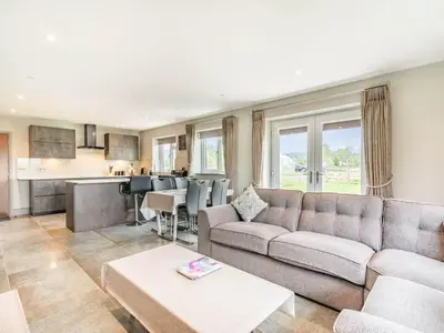 a living room with a couch and a kitchen at Mya Cottage in Wilpshire