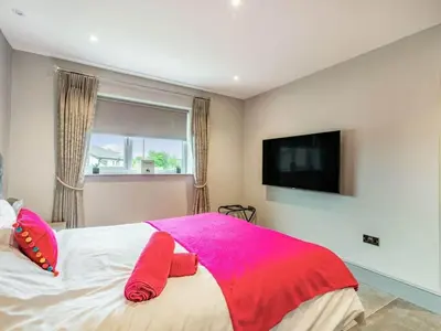 a bedroom with a bed with pink pillows and a tv at Mya Cottage in Wilpshire