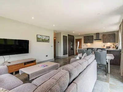 a living room with a large couch and a kitchen at Mya Cottage in Wilpshire