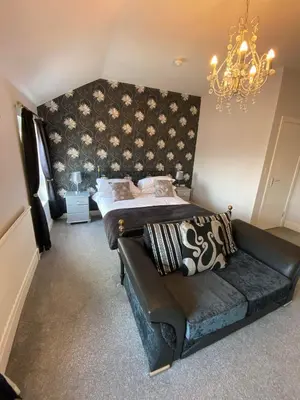 a bedroom with a bed and a couch and a chandelier at Edenfield Number 42 in Blackpool