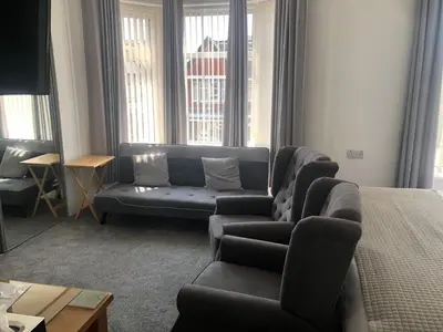 a living room with a couch and a chair and windows at Edenfield Number 42 in Blackpool