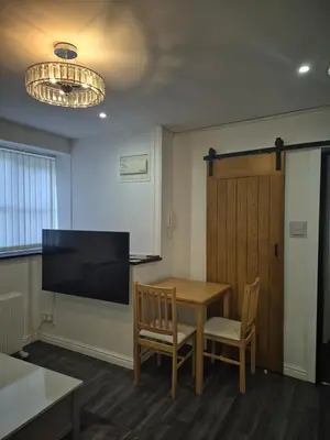 a room with a table and a flat screen tv at Town Centre Maisonette in Ulverston