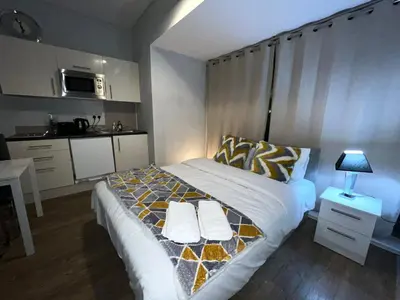 a bedroom with a bed and a small kitchen at Moorfield Liverpool City Studios in Liverpool