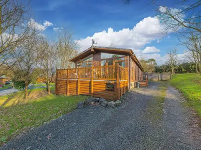 a large wooden house on a gravel road at Fern Lodge in Grange Over Sands