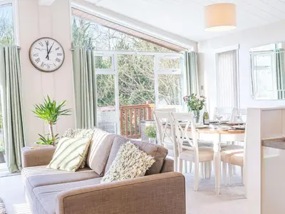 a living room with a couch and a table with a clock at Fern Lodge in Grange Over Sands