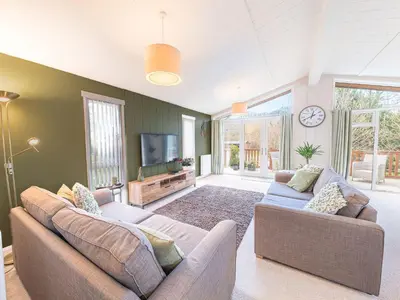 a living room with two couches and a flat screen tv at Fern Lodge in Grange Over Sands