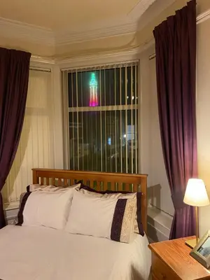 a bedroom with a bed and a window with purple curtains at The Laurels in Blackpool
