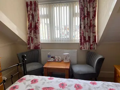 a bedroom with a bed and two chairs and a table at The Laurels in Blackpool