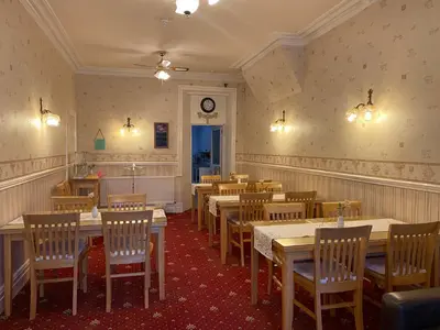 a restaurant with tables and chairs and a clock on the wall at The Laurels in Blackpool