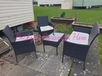 a patio with chairs and a table with a sign on it at Becky's Caravan at Marton Mere in Blackpool