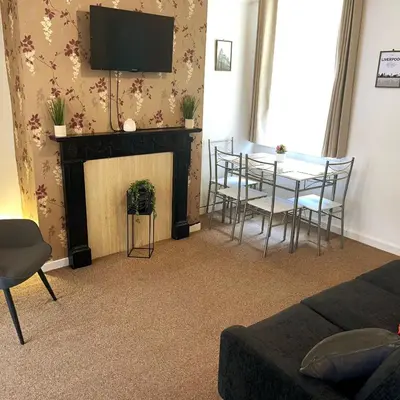 a living room with a table and chairs and a fireplace at Rooms Anfield- 5 mins from LFC in Liverpool