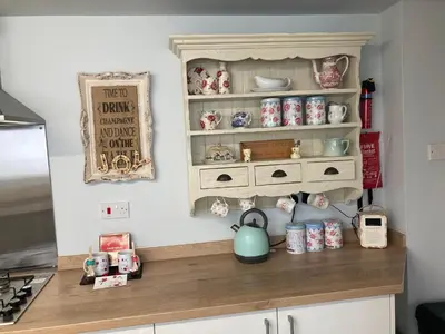 a kitchen counter with a cupboard filled with dishes at Adlington Cottage, Lancashire in Adlington