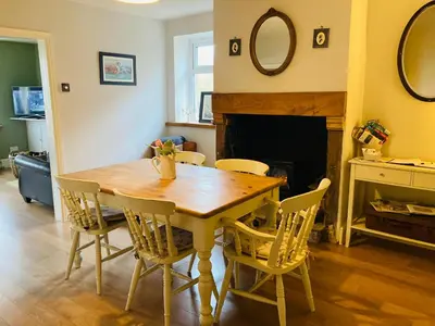 a dining room table with chairs and a fireplace at Adlington Cottage, Lancashire in Adlington