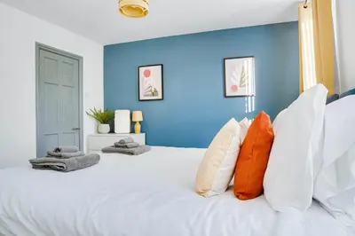a blue bedroom with a large white bed with orange pillows at Cosy 3 bedroom house near Anfield Stadium in Liverpool