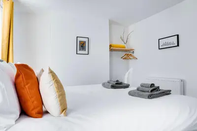 a white bed with pillows and towels on it at Cosy 3 bedroom house near Anfield Stadium in Liverpool