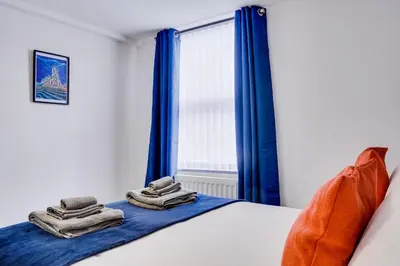 a bedroom with blue curtains and a bed with towels at Cosy 3 bedroom house near Anfield Stadium in Liverpool