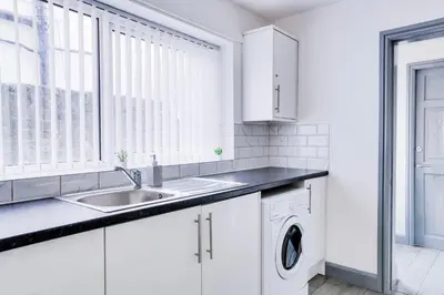 a white kitchen with a sink and a washing machine at Cosy 3 bedroom house near Anfield Stadium in Liverpool