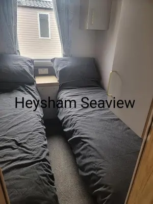 two beds in a small bedroom with a window at Heysham seaview in Heysham