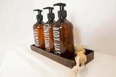 a shelf with three bottles of soap and a brush at Mulberry Cottage - Cosy 3 Bed Cottage near Lytham Windmill in Lytham St Annes