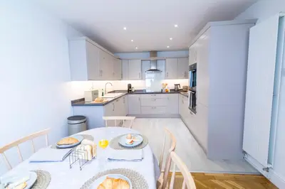 a kitchen with a table and chairs and a kitchen with white cabinets at Mulberry Cottage - Cosy 3 Bed Cottage near Lytham Windmill in Lytham St Annes