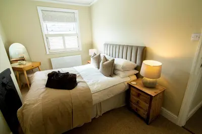 a bedroom with a bed with a bag on it at Mulberry Cottage - Cosy 3 Bed Cottage near Lytham Windmill in Lytham St Annes