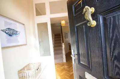 a black door with a snake on it next to a hallway at Mulberry Cottage - Cosy 3 Bed Cottage near Lytham Windmill in Lytham St Annes