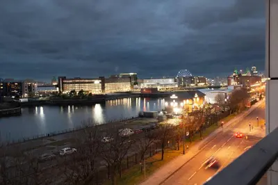a city at night with a river and buildings at Stunning Mersey View Flat w Parking in Liverpool in Liverpool